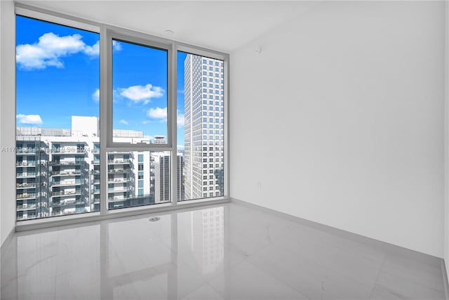 spare room with floor to ceiling windows and tile patterned flooring