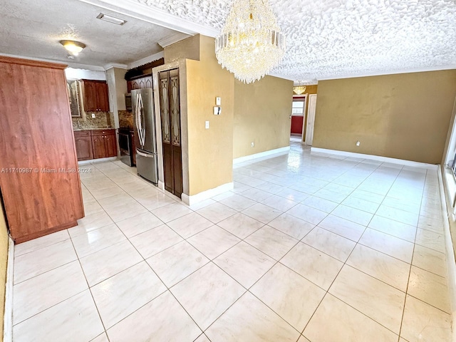 kitchen with a textured ceiling, stainless steel refrigerator, a notable chandelier, and backsplash