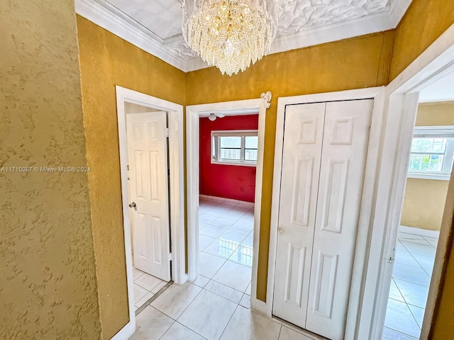 hall with light tile patterned floors, crown molding, and an inviting chandelier