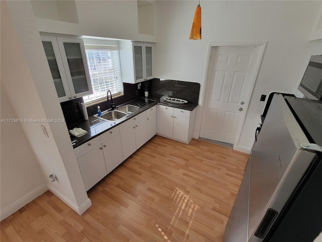 kitchen with white cabinets, tasteful backsplash, sink, and light hardwood / wood-style flooring