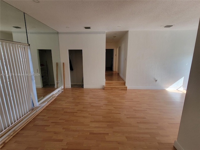 spare room featuring a textured ceiling and light hardwood / wood-style flooring