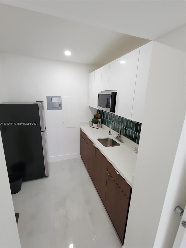 kitchen featuring backsplash, dark brown cabinetry, stainless steel appliances, sink, and white cabinetry