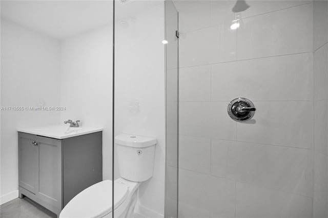 bathroom featuring vanity, toilet, and a tile shower