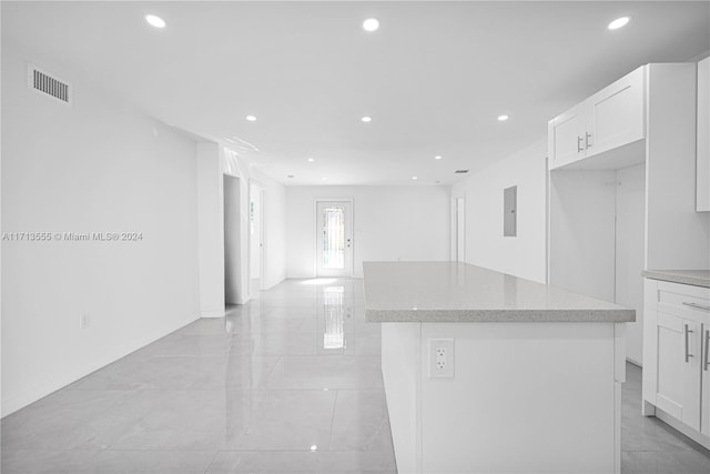 kitchen with white cabinets, electric panel, and a kitchen island