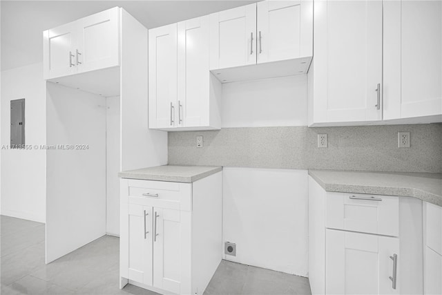 kitchen with white cabinets, backsplash, and electric panel