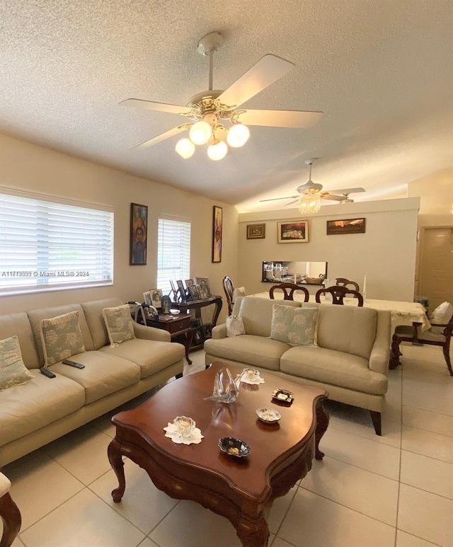 living room featuring light tile patterned floors, a textured ceiling, ceiling fan, and lofted ceiling