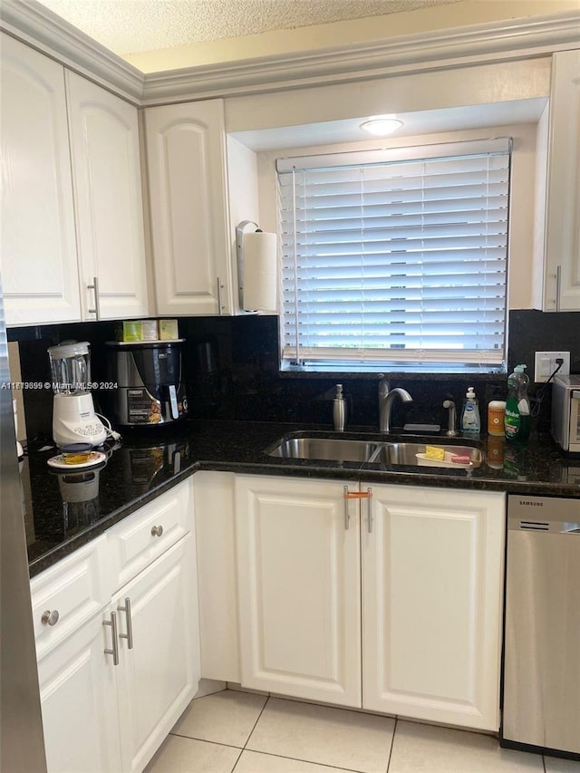 kitchen with white cabinetry, sink, light tile patterned floors, and stainless steel dishwasher