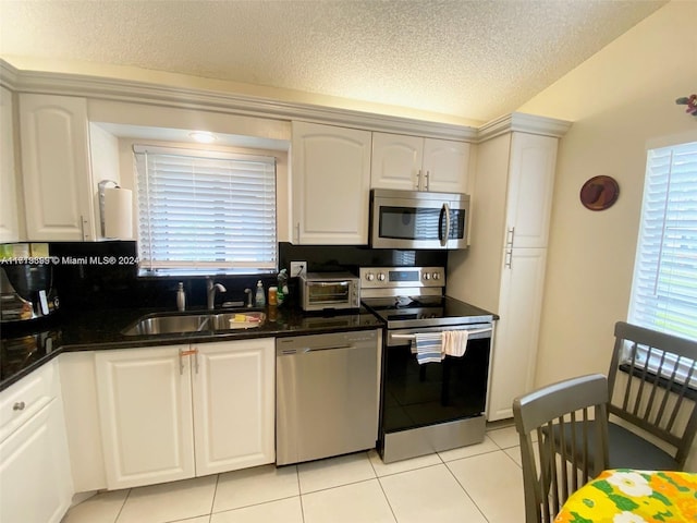 kitchen featuring white cabinets, sink, light tile patterned floors, and stainless steel appliances