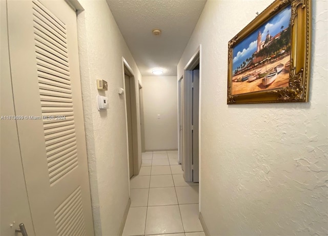 hallway with light tile patterned floors and a textured ceiling