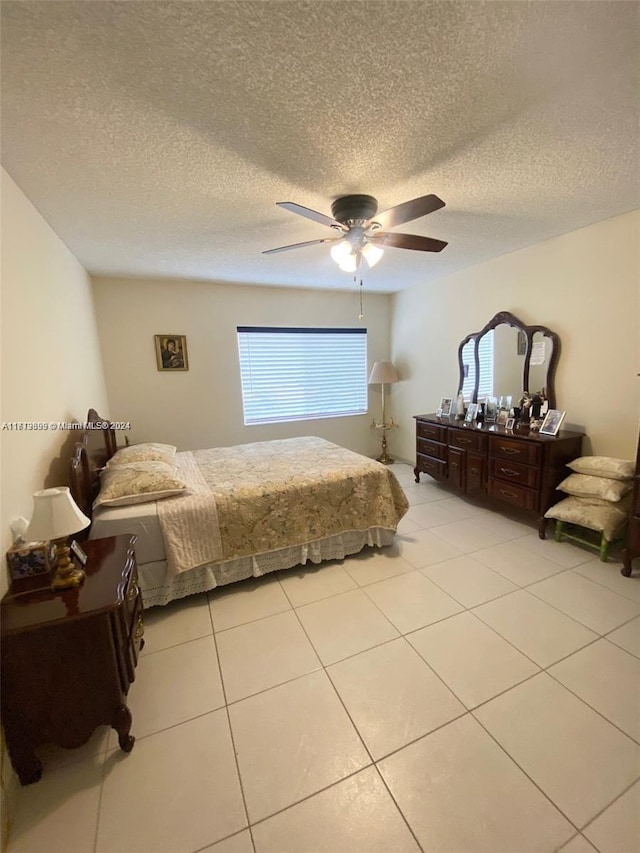 bedroom with a textured ceiling, ceiling fan, and light tile patterned flooring