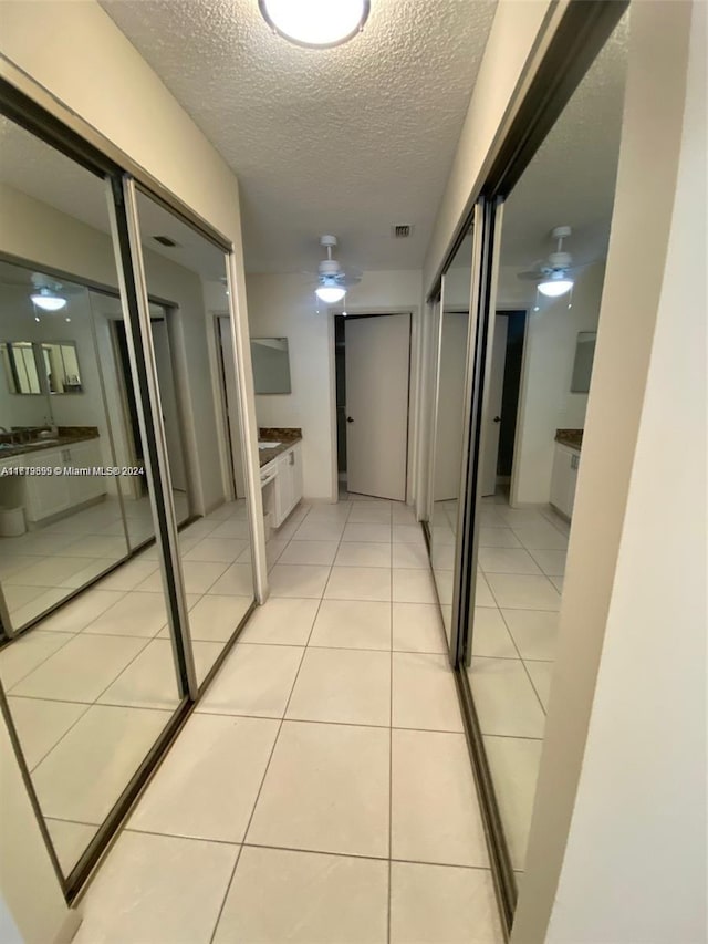 corridor featuring light tile patterned floors and a textured ceiling