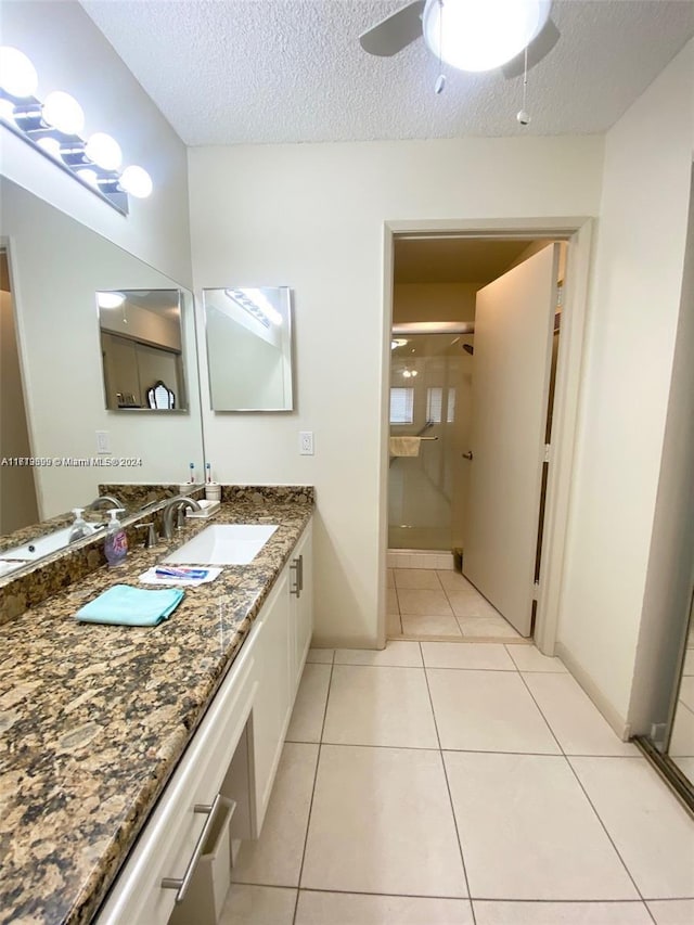 bathroom with tile patterned floors, vanity, a textured ceiling, a shower with door, and ceiling fan