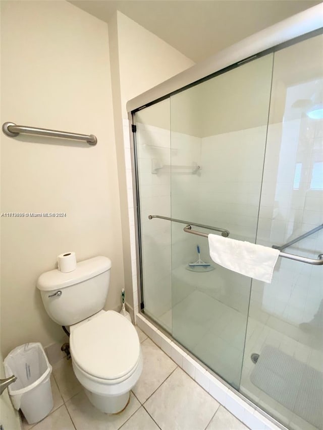 bathroom featuring toilet, tile patterned floors, and a shower with door