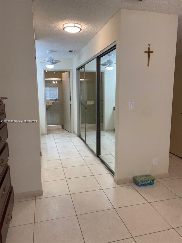 hallway featuring light tile patterned flooring and a textured ceiling