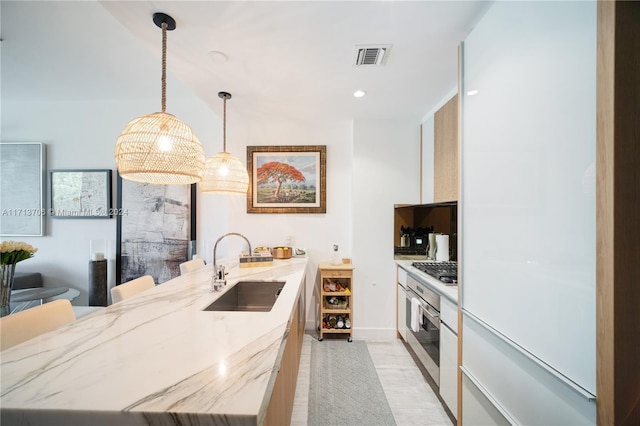 kitchen with sink, stainless steel appliances, light stone counters, pendant lighting, and a breakfast bar