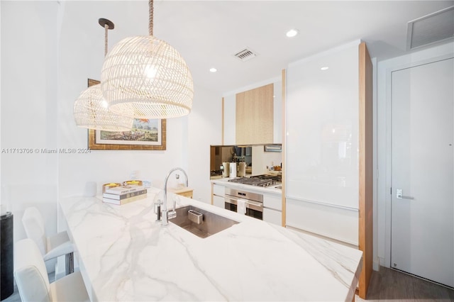 kitchen featuring sink, stainless steel appliances, hanging light fixtures, a kitchen breakfast bar, and light stone counters