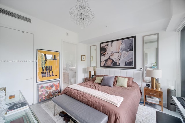 bedroom with wood-type flooring, lofted ceiling, ensuite bath, and a notable chandelier