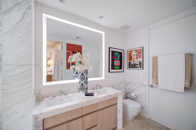 bathroom with vanity, toilet, and tile walls