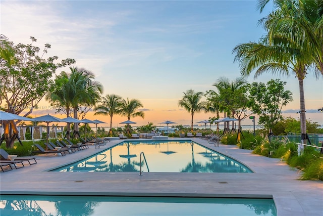 pool at dusk with a patio area