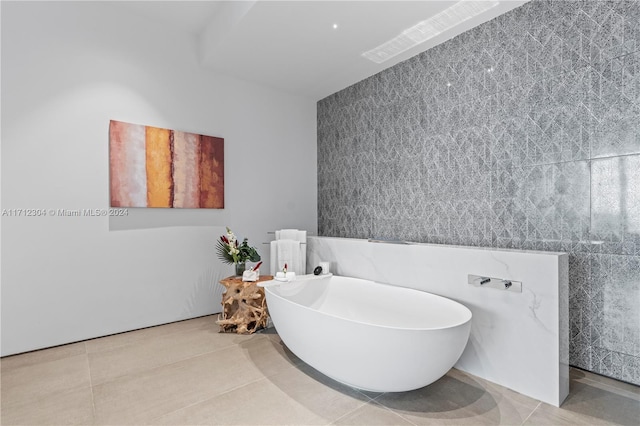 bathroom with a tub to relax in, tile patterned floors, and tile walls