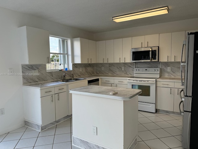 kitchen with appliances with stainless steel finishes, tasteful backsplash, a textured ceiling, sink, and a center island