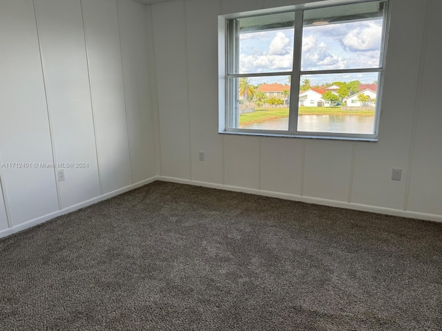 empty room with dark colored carpet and a water view