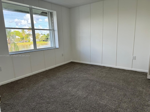 spare room with dark colored carpet