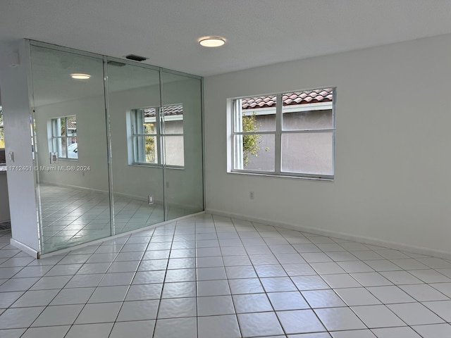 unfurnished bedroom featuring a closet, light tile patterned floors, and a textured ceiling