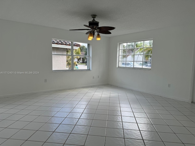 empty room featuring ceiling fan, light tile patterned floors, and a textured ceiling