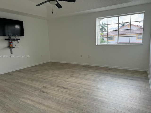 unfurnished room featuring a textured ceiling, light wood-type flooring, and ceiling fan