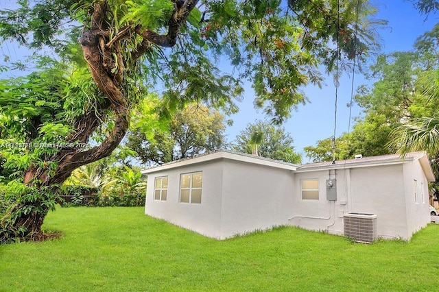 back of property featuring a lawn and cooling unit