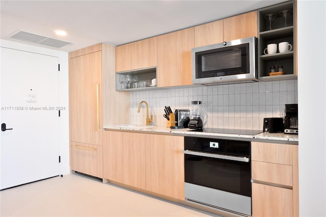 kitchen featuring light stone countertops, light brown cabinetry, wall oven, and black electric stovetop