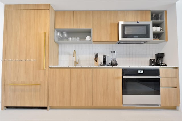 kitchen with light stone countertops, wall oven, tasteful backsplash, light brown cabinetry, and light tile patterned floors