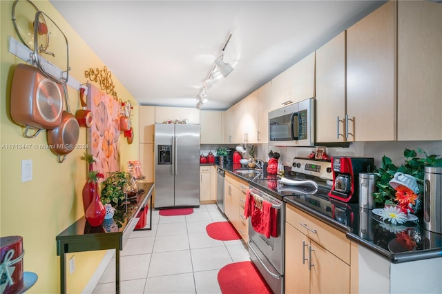 kitchen with sink, rail lighting, light brown cabinetry, light tile patterned floors, and appliances with stainless steel finishes