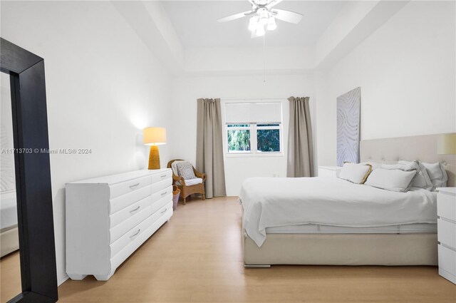 bedroom with a tray ceiling, ceiling fan, and light hardwood / wood-style floors