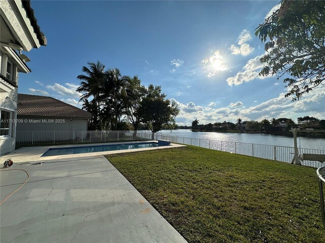 view of pool with a patio, a lawn, a water view, and a trampoline