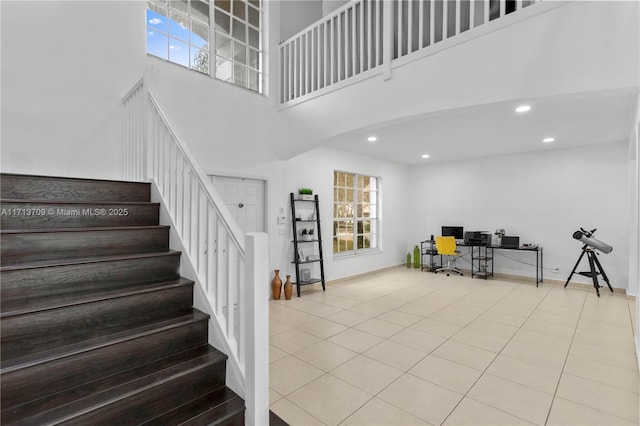 stairs with a towering ceiling, tile patterned flooring, and recessed lighting