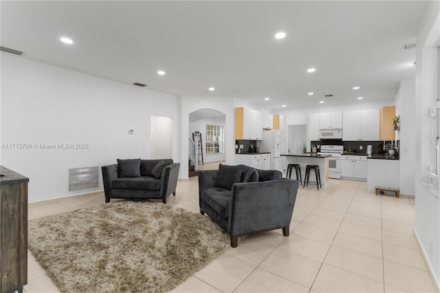 living room featuring light tile patterned flooring, arched walkways, and visible vents