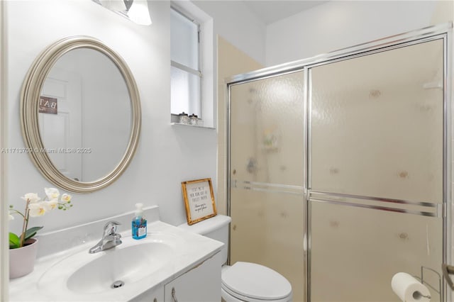 bathroom featuring toilet, a stall shower, and vanity