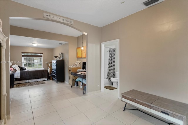 interior space with light tile patterned floors, arched walkways, visible vents, and baseboards