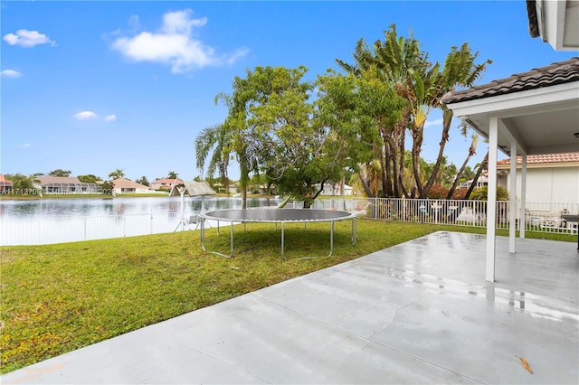 view of yard with a water view, a trampoline, a patio, and fence