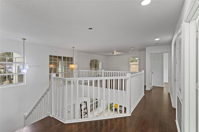 corridor with an inviting chandelier, wood finished floors, an upstairs landing, and recessed lighting