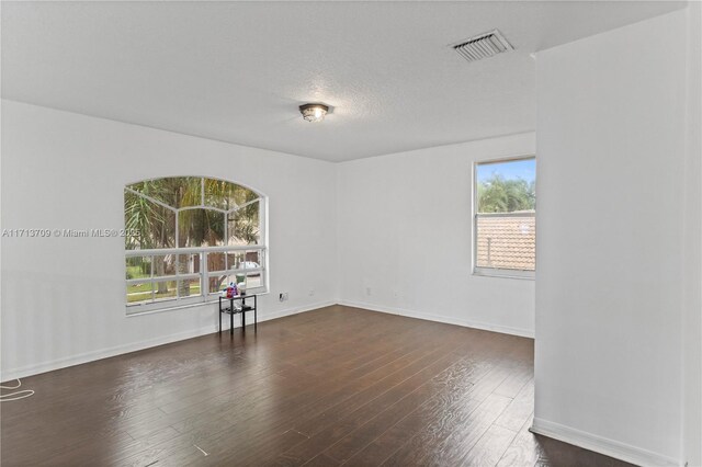 unfurnished bedroom with a textured ceiling, a closet, and dark hardwood / wood-style flooring