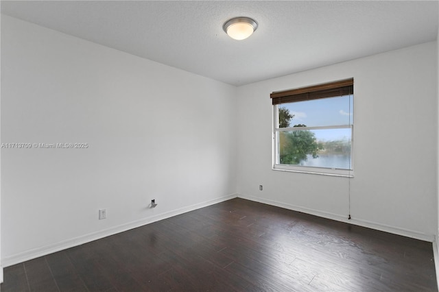 unfurnished room featuring baseboards, a textured ceiling, and dark wood-style floors