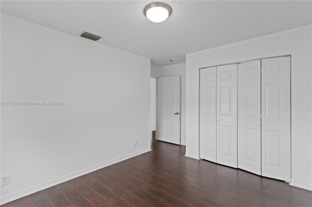 unfurnished bedroom featuring visible vents, baseboards, dark wood finished floors, a closet, and a textured ceiling