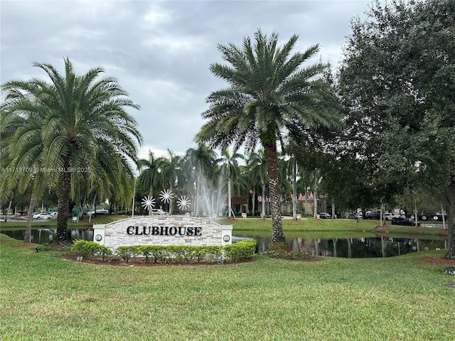 community sign with a lawn and a water view