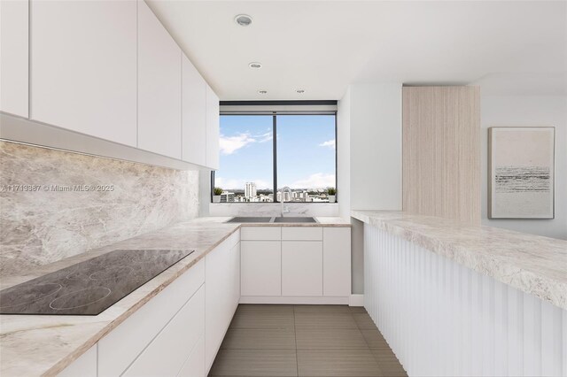 kitchen with black electric cooktop, white cabinetry, tile patterned flooring, and sink