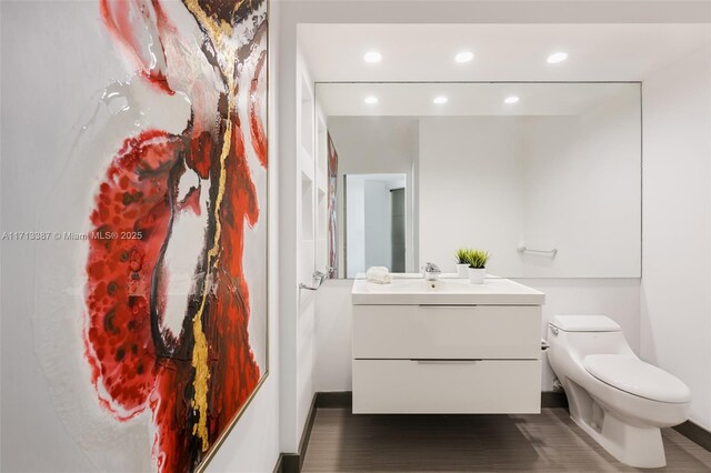 bathroom with vanity, toilet, and hardwood / wood-style floors