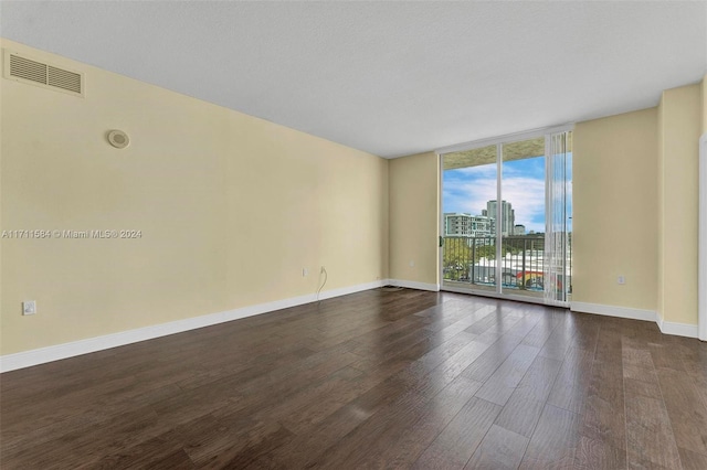 empty room with expansive windows and dark hardwood / wood-style flooring