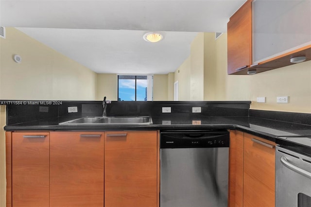 kitchen featuring stainless steel dishwasher, dark stone countertops, range, and sink